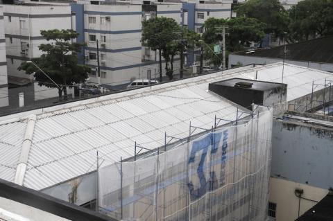 prédio com cobertura concluída e rede na fachada demonstrando a execução de serviços. #paratodosverem