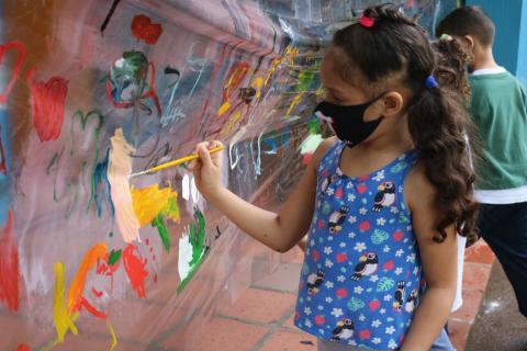 Criança pinta em plástico #paratodosverem