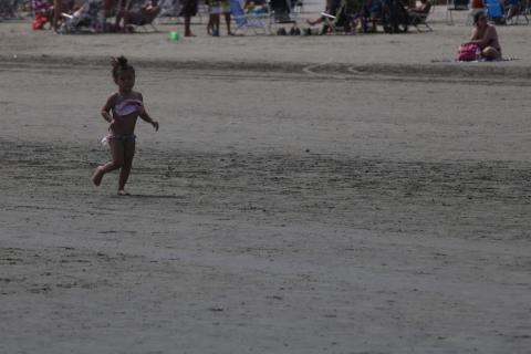 criança correndo na areia da praia #paratodosverem