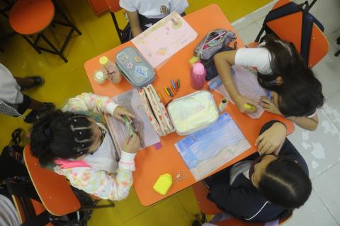 crianças desenham na sala da aula #paratodosverem