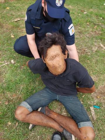 Homem com rosto borrado sendo detido pela guarda. #paratodosverem