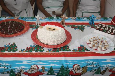 Bolo e doces com símbolos natalinos sobre uma mesa. #paratodosverem