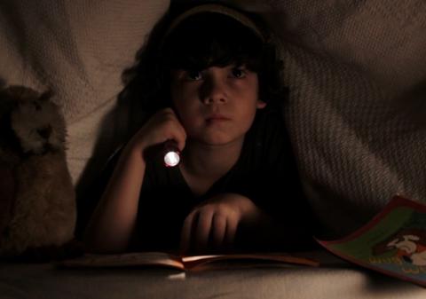 Menino segura lanterna no escuro. Cena de O pequeno monstro. #paratodosverem