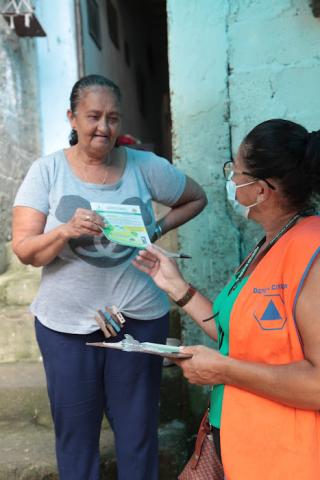 profissional da defesa civil entrega panfleto para mulher #paratodosverem