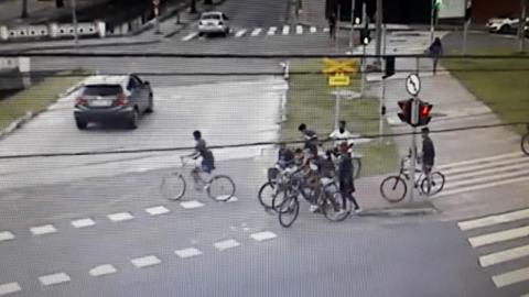 homens fogem de bicicleta em área próxima à linha do VLT. #paratodosverem