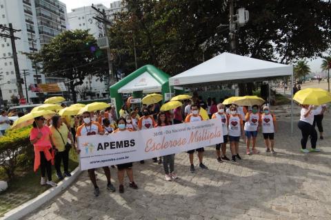 pessoas na caminhada com faixa e guarda chuvas amarelos #paratodosverem