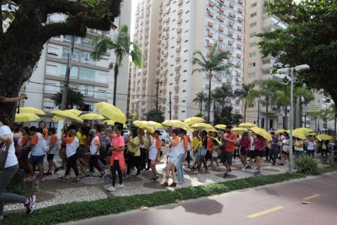 pessoas na caminhada com faixa e guarda chuvas amarelos #paratodosverem