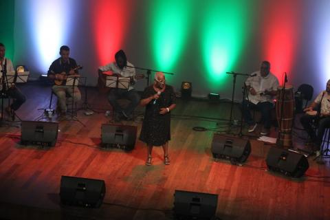 Sandrinha canta no palco com banda ao fundo. #paratodosverem