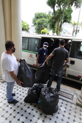 homens carregam sacos plásticos cheios para colocar dentro de van. #paratodosverem