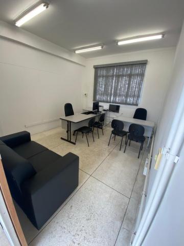 Sala com sofá, mesas e cadeiras de escritório. #paratodosverem