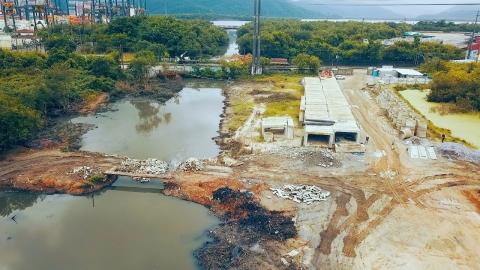 vista geral de canal, com aduelas no solo ao lado direito. À esquerda e à frente, vegetação. #paratodosverem