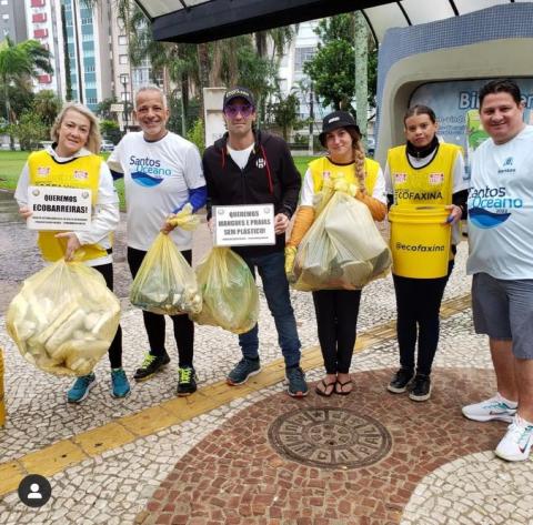 Equipe de voluntários segura sacos plásticos com resíduos coletados. #paratodosverem