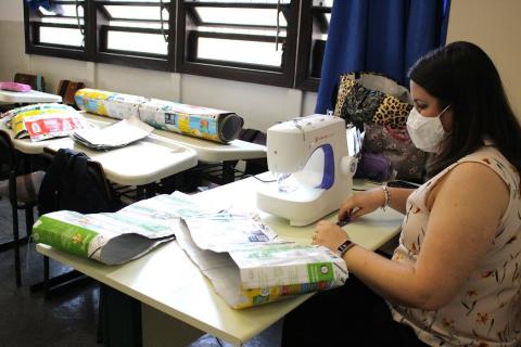 Professora com máquina costura caixas de leite #paratodosverem