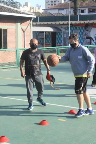 professor acompanha percurso com bola feito por aluno. #paratodosverem