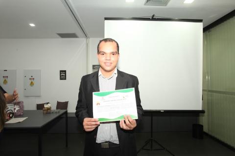 Caio Ryan Rodrigues, de terno, exibe certificado. #paratodosverem