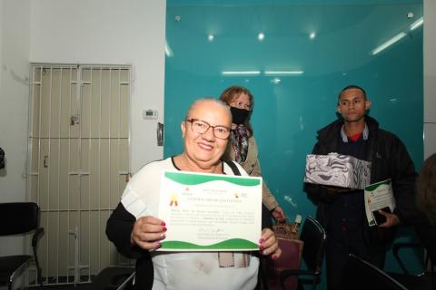 Maria Alice de Souza Carvalho sorri e mostra certificado. #paratodosverem