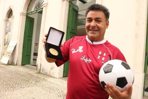 Ricardinho segura medalha dentro de caixa na mão direita e a bola, na esquerda. #paratodosverem