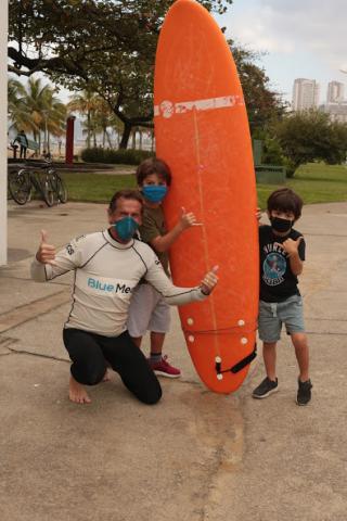 Cisco Araña com crianças e prancha de surfe. #pracegover