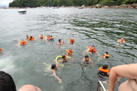 visitantes estão tomando banho de mar, todos com colete salva-vidas. #paratodosverem