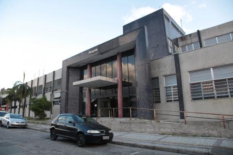 Fachada do hospital com veículo preto estacionado em frente. #pracegover