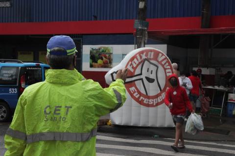 Agente da CET faz gesto do braço estendido para pedestre atravessar. #paratodosverem