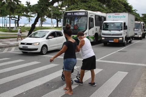 mulher atravessa na faixa auxiliando idoso. Os veículos estão parados atrás da faixa de pedestres. #paratodosverem