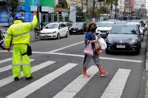 Agente da CET sinaliza para trânsito parar enquanto mulher atravessa. #paratodosverem