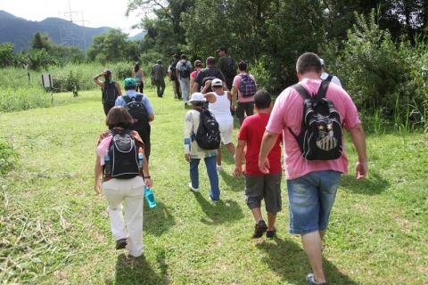 turistas iniciam trilha na grama e próxima a vegetação mais alta. #paratodosverem