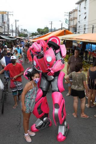 criança posa para foto ao lado de megatron. Há movimento nas barrocas. #paratodosverem