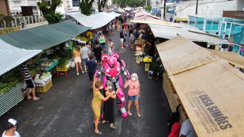 megatron interagem com mulheres no meio da rua, entre as barracas. #paratodosverem