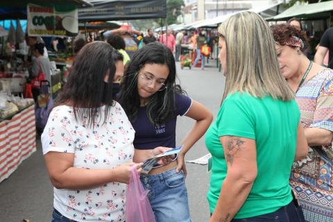 Mulher e adolescente observam material entregue por técnicos da Prefeitura. #pratodosverem