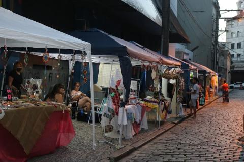 Barracas de feira de artesanato em rua ao anoitecer. #paratodosverem