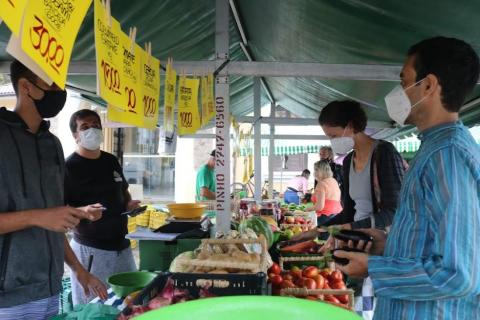 Comerciantes e consumidores conversam em barraca de legumes e vegetais. #pracegover