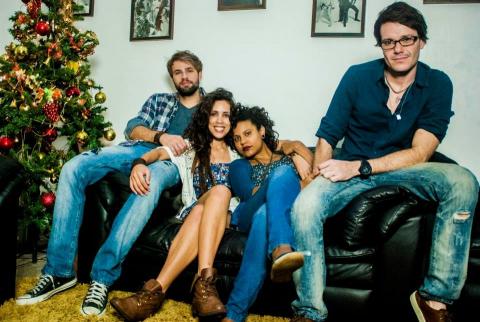 duas mulheres e dois homens sentados em um sofá ao lado de uma árvore de natal. #paratodosverem