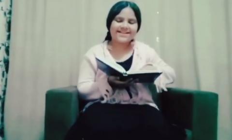 menina está sentada em poltrona lendo um livro. #paratodosverem