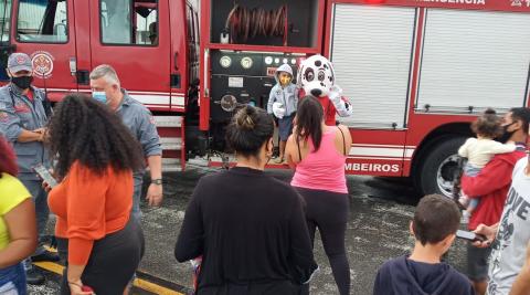 Famílias tiram fotos com personagem infantil em frente ao caminhão dos Bombeiros. #pracegover