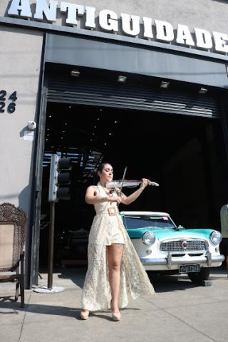 Violinista se apresenta em frente a antiquário e carro antigo. #pratodosverem