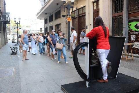 Mulher tira fotografia em xícara gigante instagramável no bulevar da Rua XV. #pratodosverem