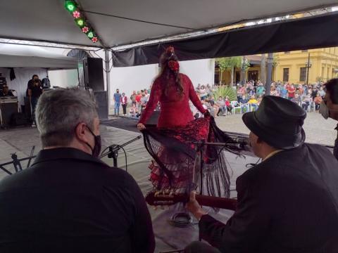 Músicos e dançarina espanhola se apresentam no palco com público ao fundo. #pracegover