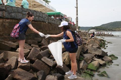 Voluntários recolhem lixo encontrado entre as rochas. #paratodosverem