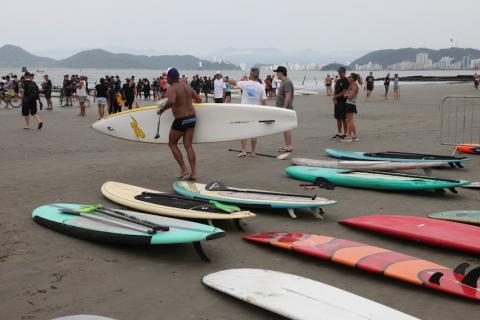 Homem carrega prancha na faixa de areia. #paratodosverem