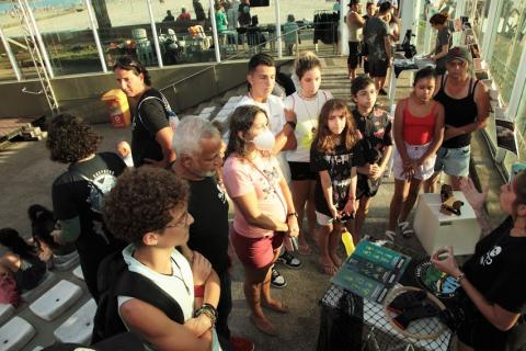 Jovens observam ambientalista em estande. #pratodosverem