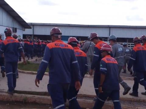 Homens uniformizado e usando capacete estão entrando em um ambiente, espécie de galpão. #paratodosverem