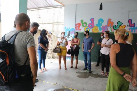 visitantes estão em área interna de escola reunidos em roda e conversando. #paratodosverem