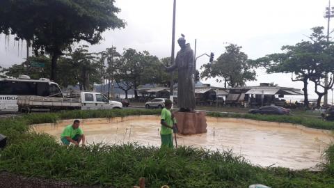 dois homens uniformizados estão dentro da área da fonte, sem água, e com a estátua de Santo Antonio ao centro. #paratodosverem