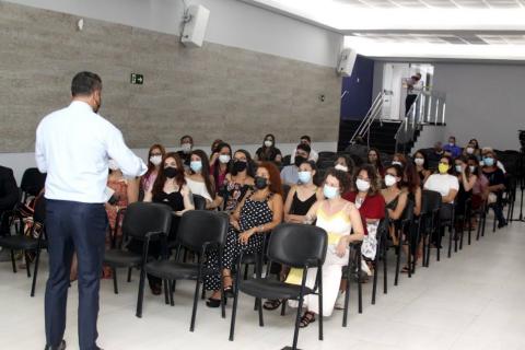 homem está de costas para a foto falando para o auditório onde há várias pessoas sentadas. #paratodosverem