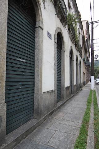 Calçada de pedras em rua, com portas de estalecimentos fechadas ao lado esquerdo. #paratodosverem