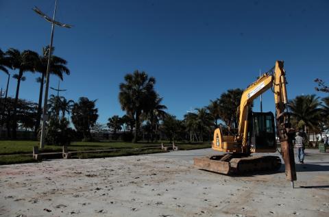 Trator em cima de chão de cimento com jardim ao fundo. #paratodosverem