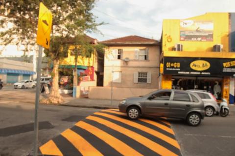 Foto da via, com a lombada no meio e carro passando sobre ela - #paratodosverem