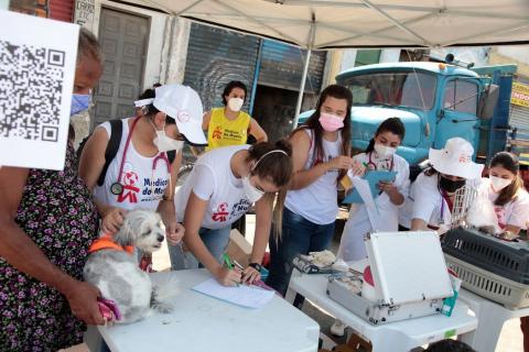 profissionais atrás de mesa e mulher segurando cachorro #paratodosverem